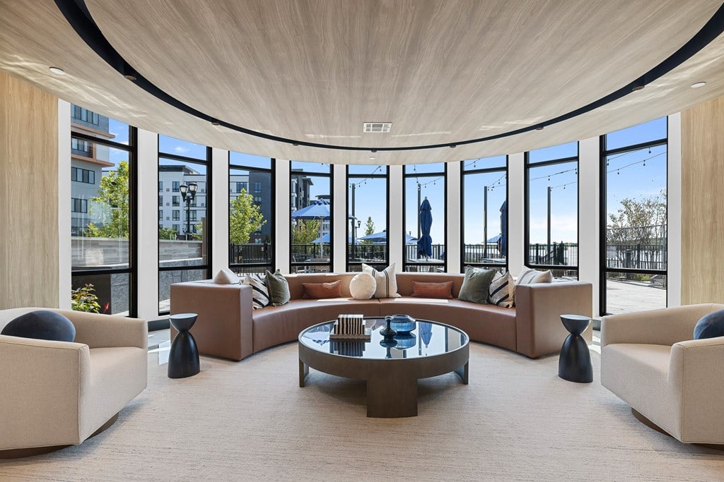 A modern living room with a large circular window and a glass table.