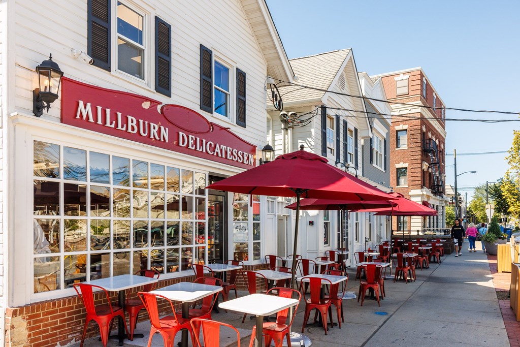 A restaurant named Millburn Delicatessen has tables and chairs set up outside.