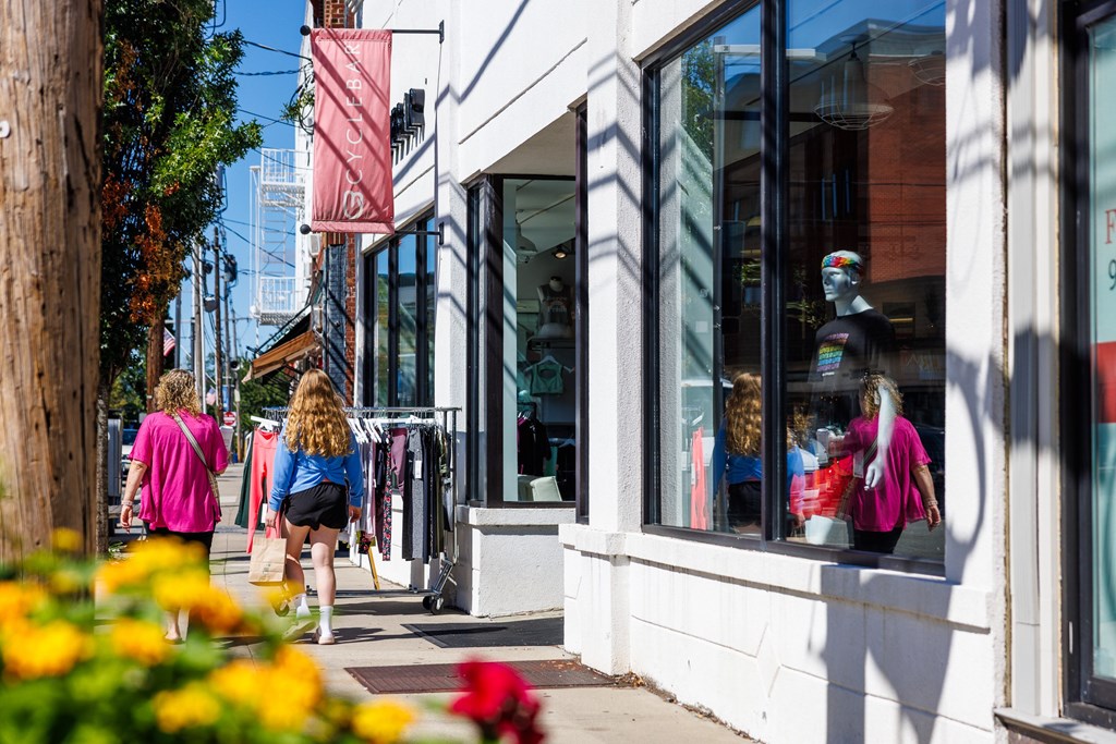 Two women walking down a street past a storefront.
