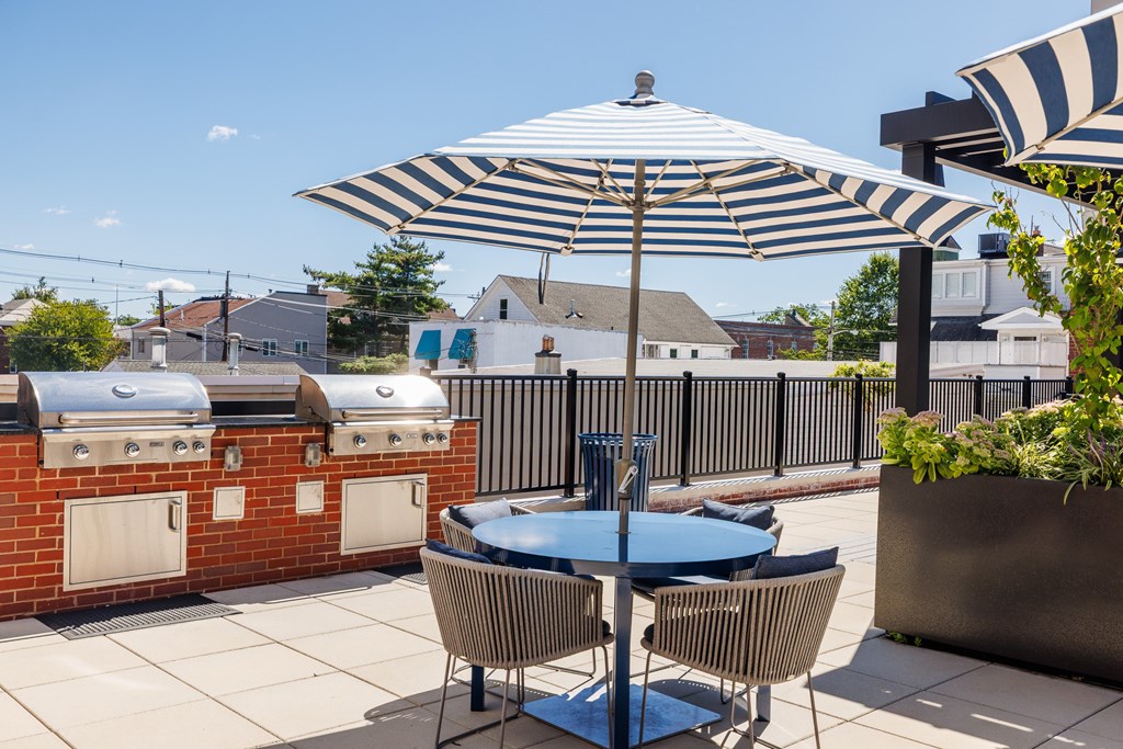 A patio with a table and chairs under a striped umbrella.