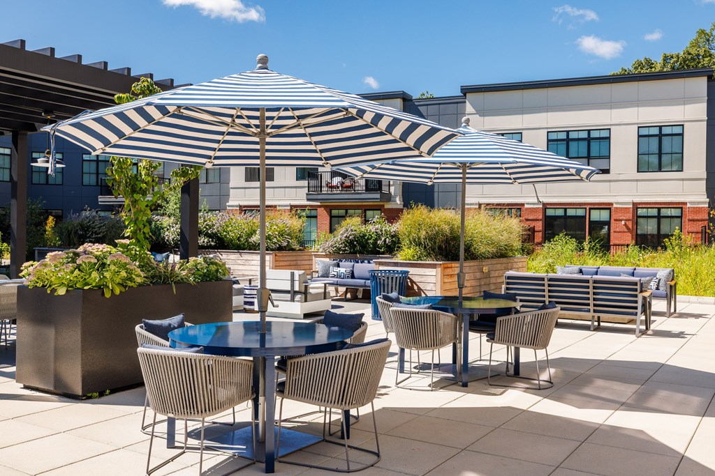 A patio with a table and chairs under a striped umbrella.