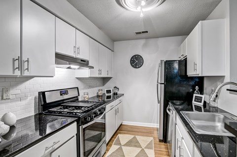 A kitchen with a black stove top oven and a black refrigerator.