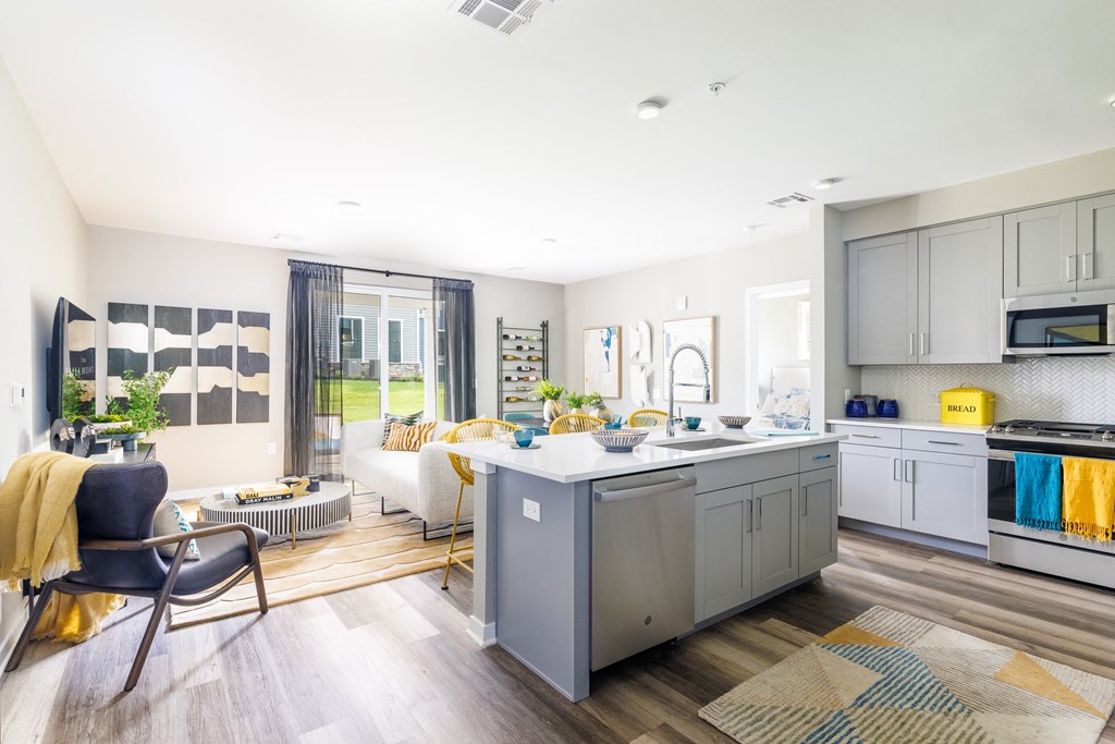 a kitchen and living room with white walls and hardwood floors