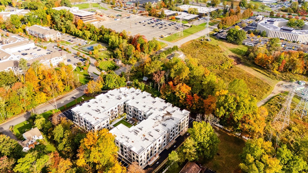 An aerial view of a large white building surrounded by trees with autumn foliage.