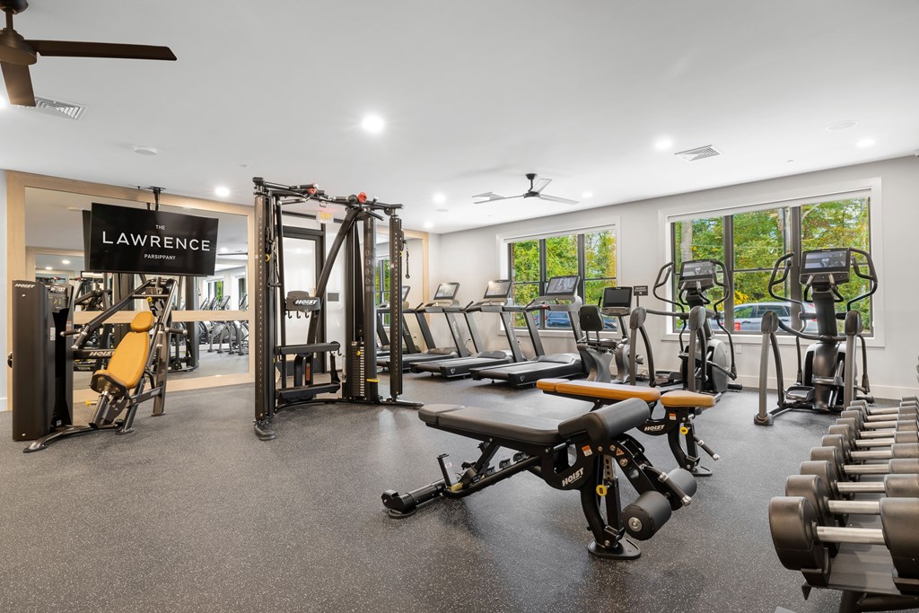 A gym with a variety of equipment including treadmills, weights, and exercise machines.