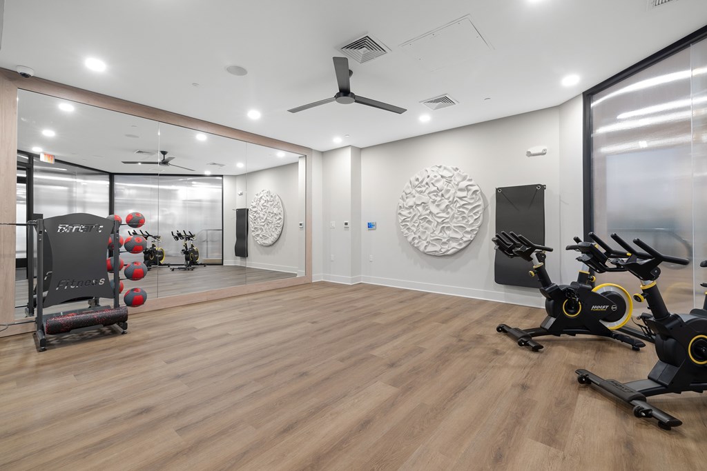 A gym with a wooden floor and exercise equipment.