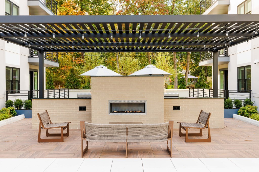 A patio with a fireplace and chairs under a pergola.