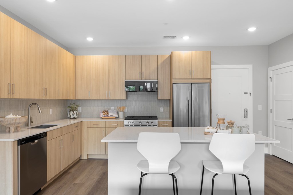 A modern kitchen with wooden cabinets and white countertops.