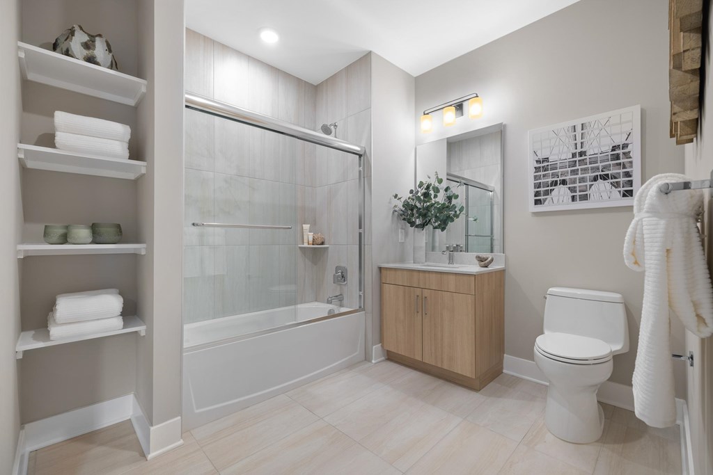 A bathroom with a glass shower door, a toilet, a sink, and a towel rack.