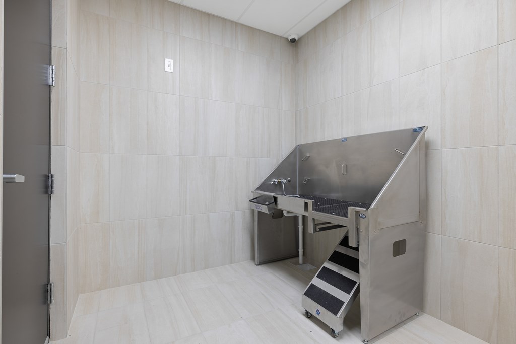 A stainless steel sink in a room with white tiled walls.