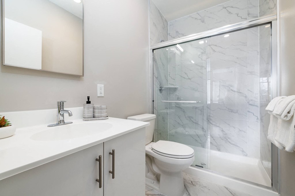 a bathroom with a white sink and toilet next to a shower with a glass door