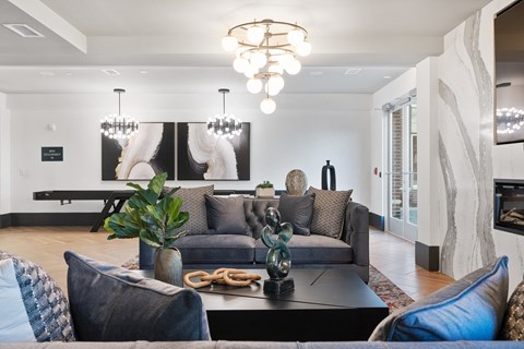 A modern living room with a grey couch and a large painting on the wall.