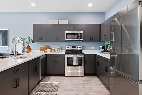 A modern kitchen with a stainless steel refrigerator and a center island with a sink.