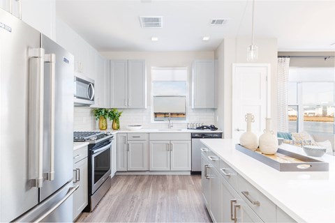 a white kitchen with stainless steel appliances and white counter tops