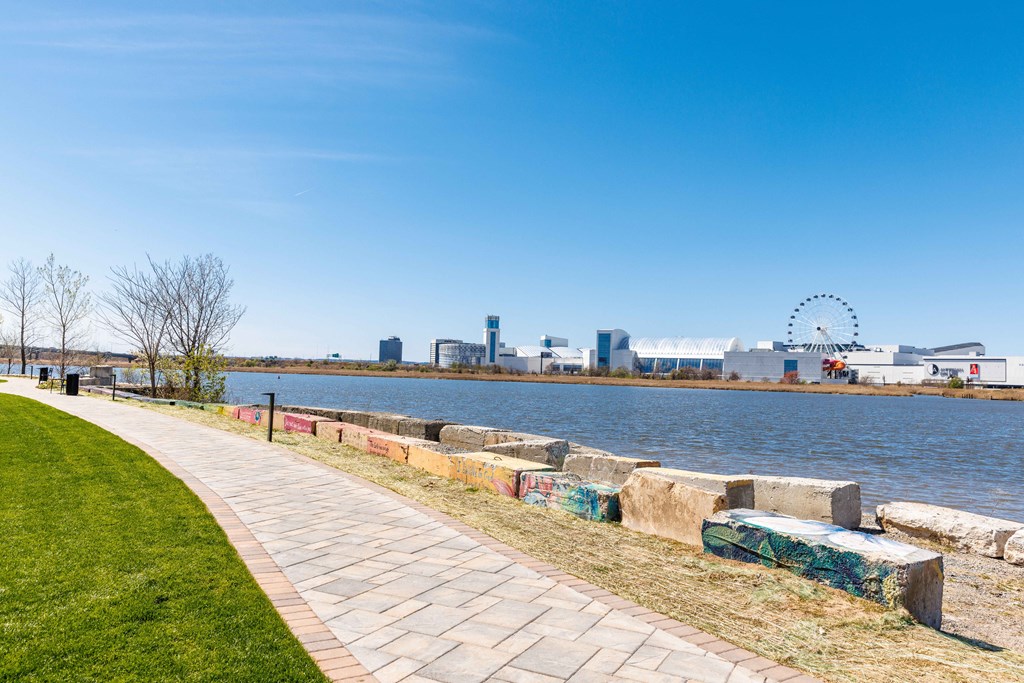a walkway along the water with the city skyline in the background
