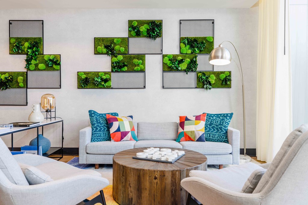 a living room with couches and a table with plants on the wall