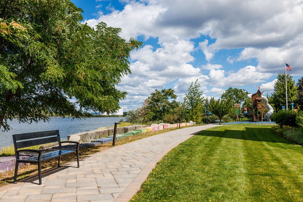 A park with a bench and a pathway leading to a body of water.