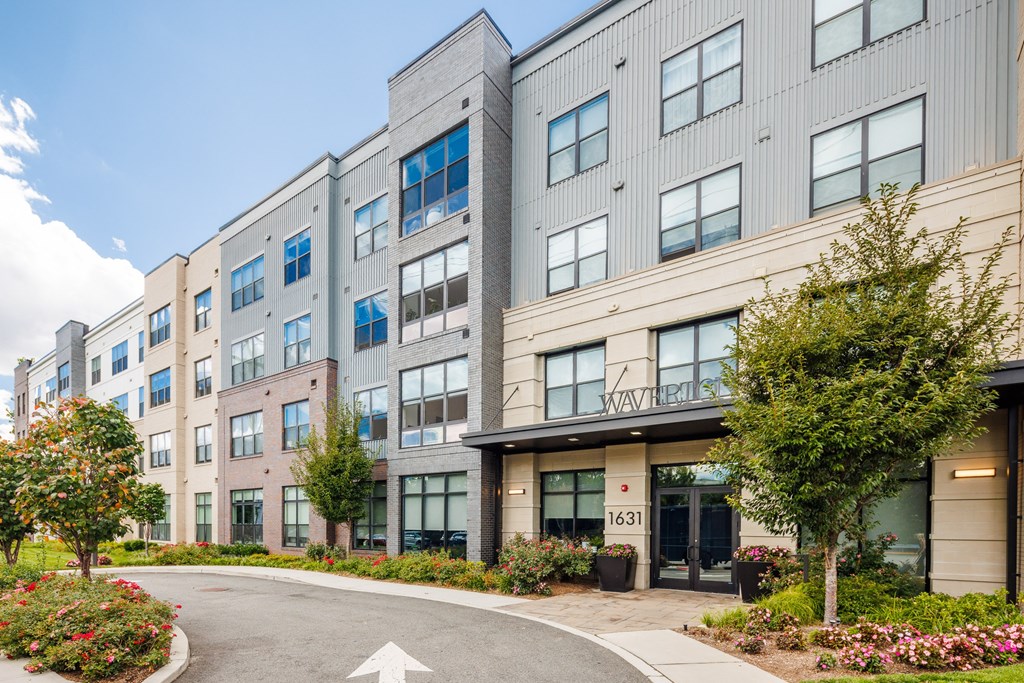 A modern apartment building with a white arrow on the road in front.