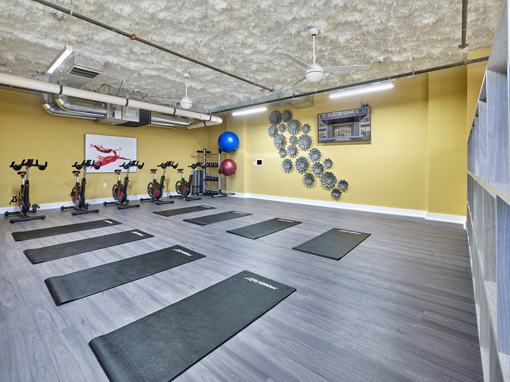 a yoga room with yoga mats on the floor and a yellow wall with bikes
