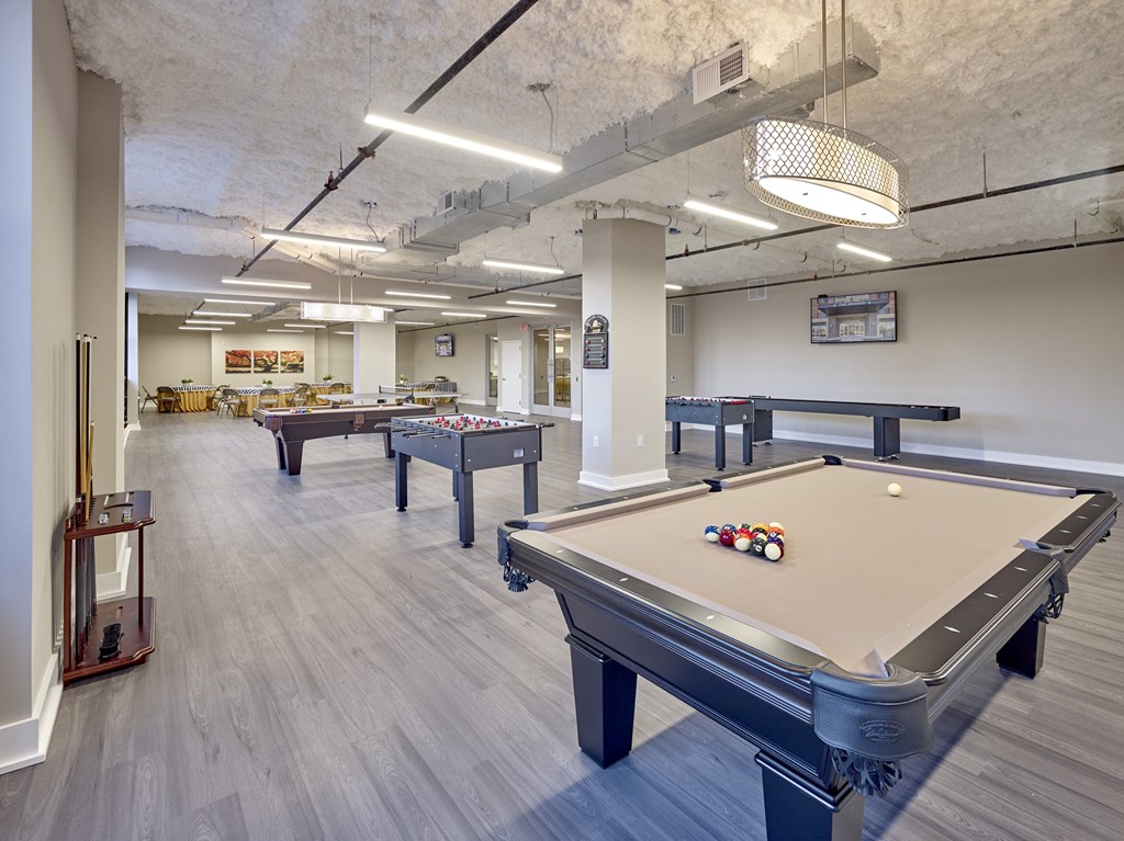 two pool tables in a community room with other billiard tables