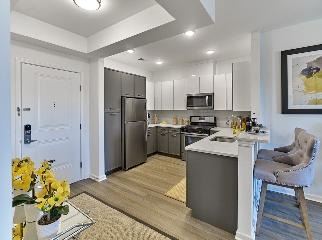 a kitchen and living room with stainless steel appliances and a white counter top