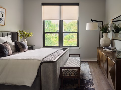 A bedroom with a large bed and a window with blinds.