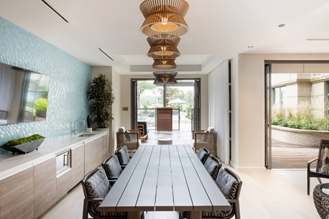 A long wooden table is surrounded by chairs in a modern dining room.