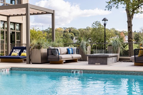 A pool area with a wooden pergola and lounge chairs.