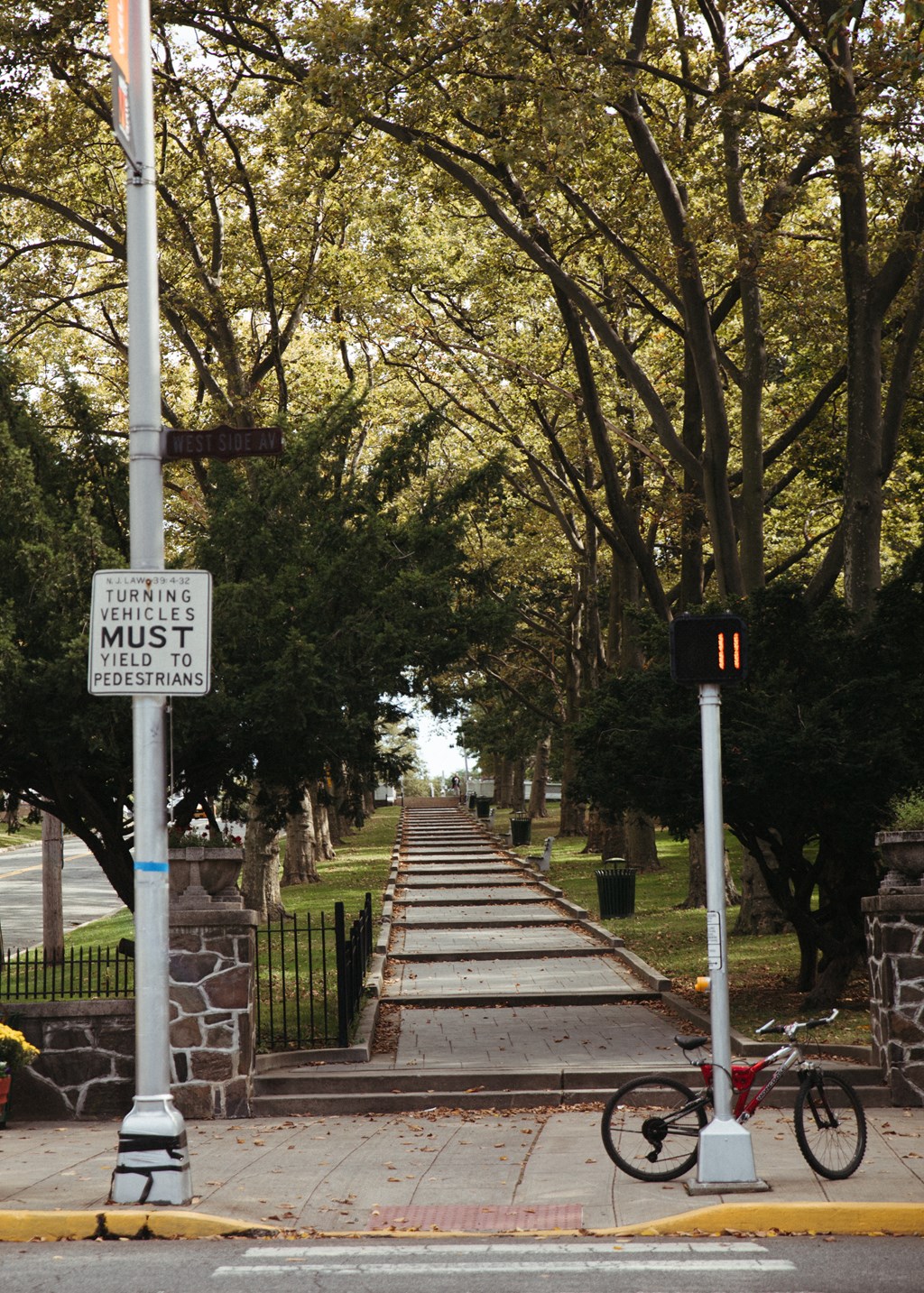 a bicycle parked on the sidewalk in front of a tree lined street