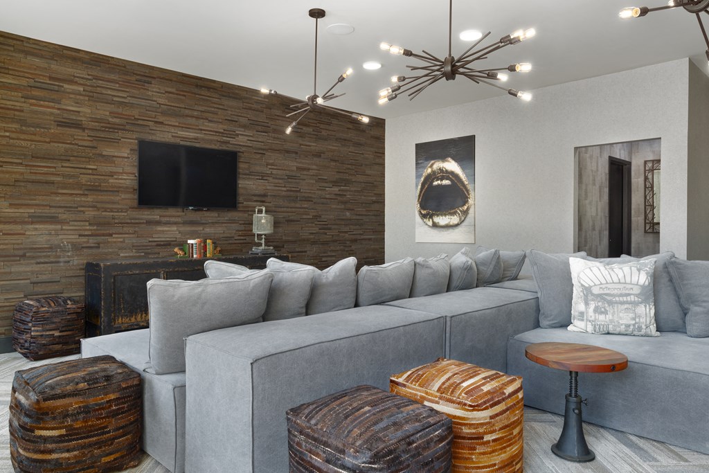 a living room with a gray couch and a brick wall