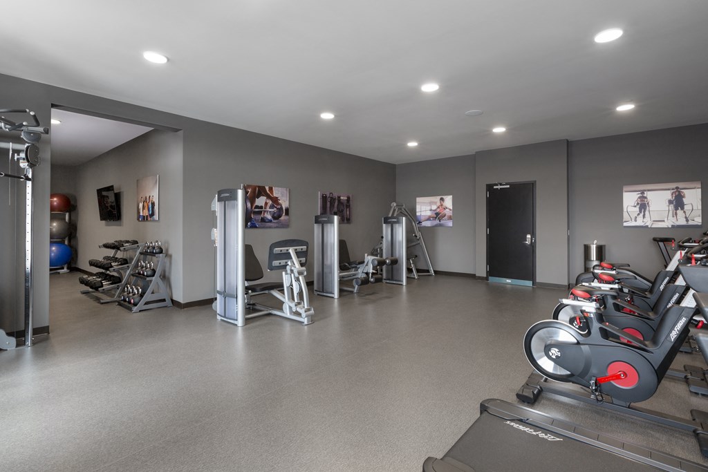 a gym with treadmills and other exercise equipment in a building with gray walls