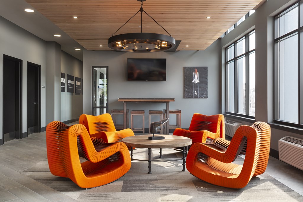 a lounge area with orange chairs and a table