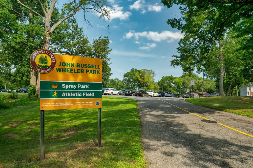 A sign for John Russell Wheeler Park is shown in front of a tree.