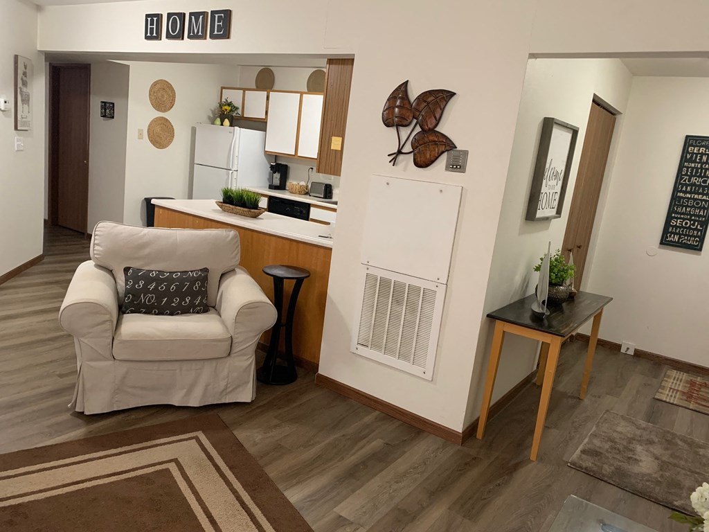 a living room with a white chair and a kitchen