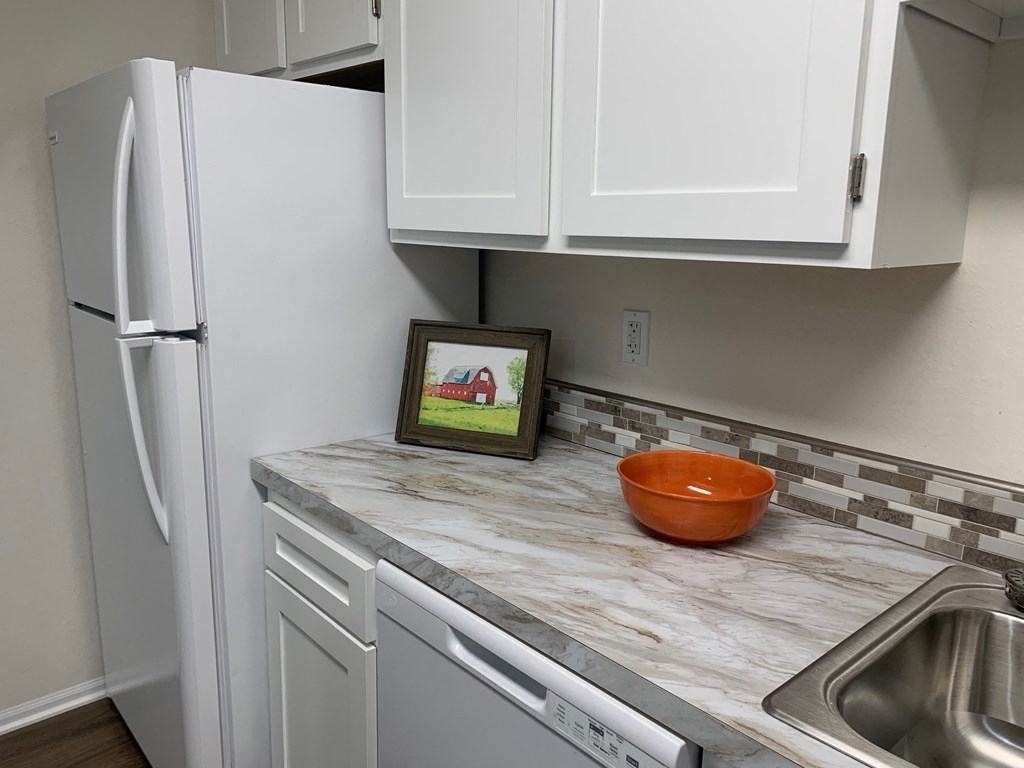 a kitchen with white cabinets and a sink and a refrigerator