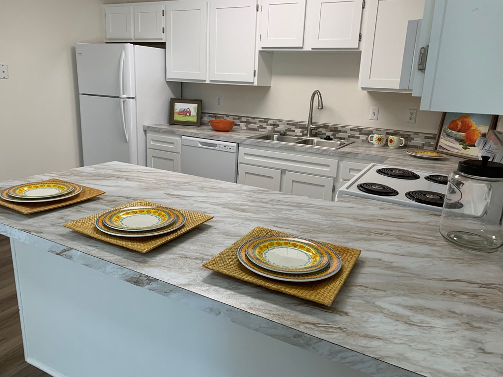 a kitchen with white cabinets and a counter with plates on it