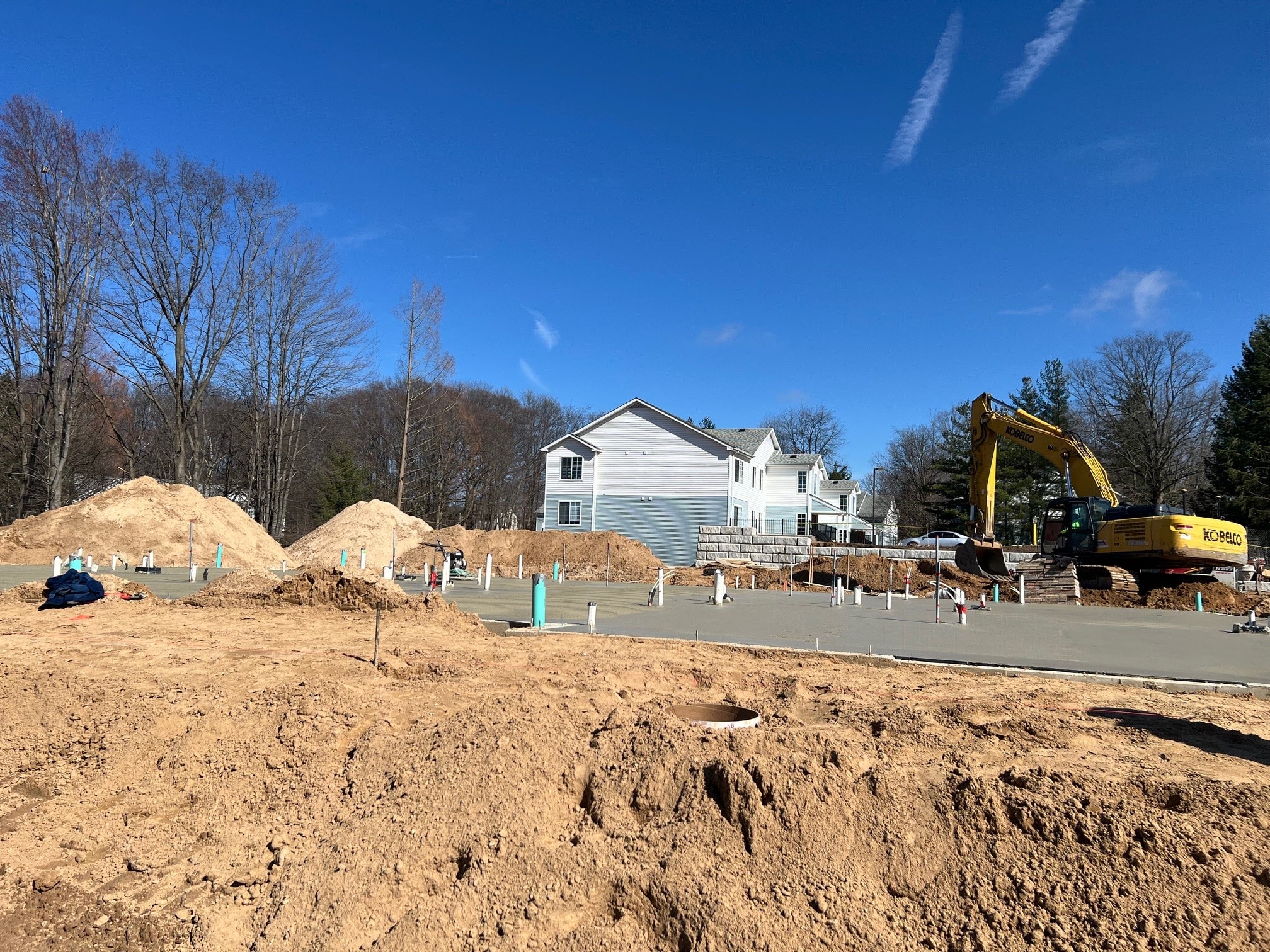 a house under construction with a construction site and a yellow excavator