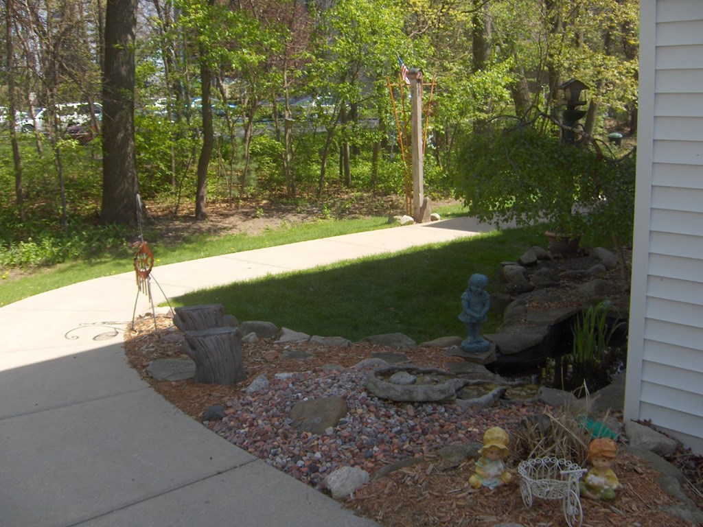 the side yard of a house with a garden and a sidewalk