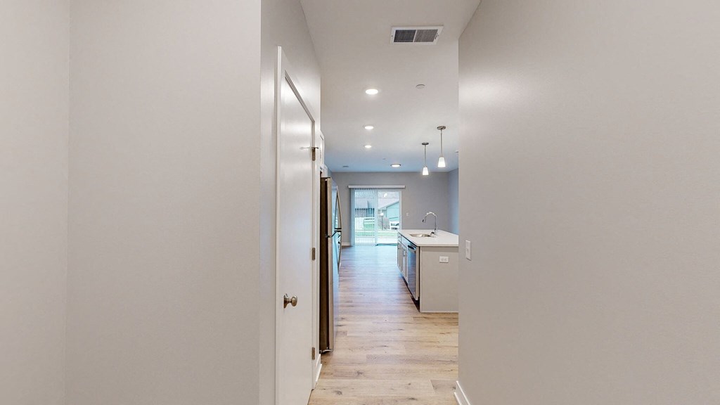 A long hallway with a kitchen at the end.