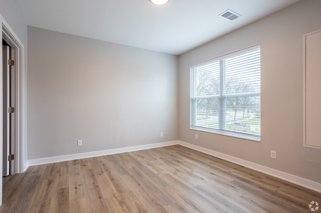 A room with wooden flooring and a window with blinds.