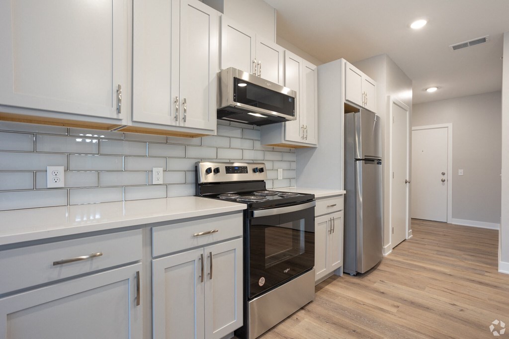 A kitchen with white cabinets and a stainless steel refrigerator.