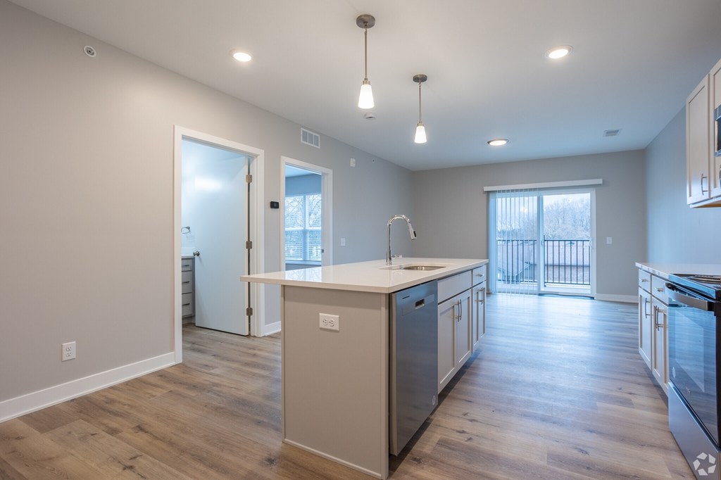 A kitchen with a white counter top and wooden floors.