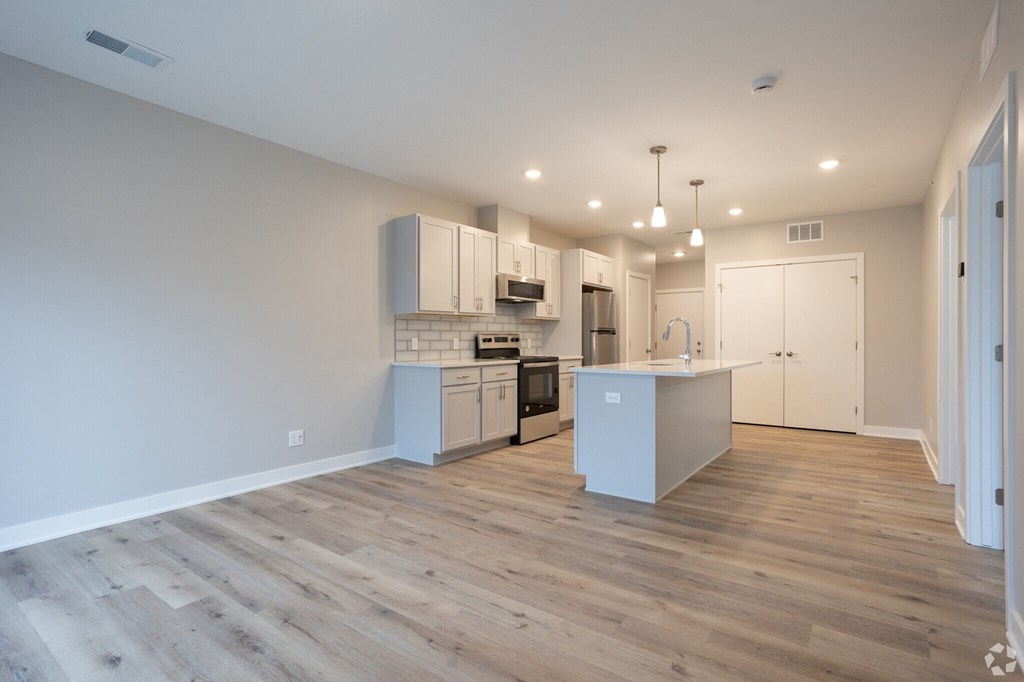 A kitchen with white cabinets and a wooden floor.