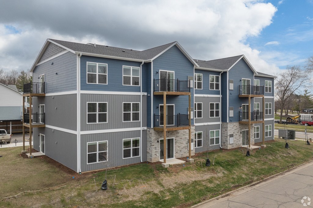 A large two-story building with balconies and a grey and blue exterior.