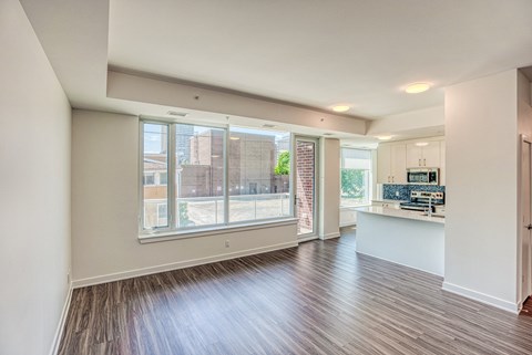an empty living room and kitchen with a large window
