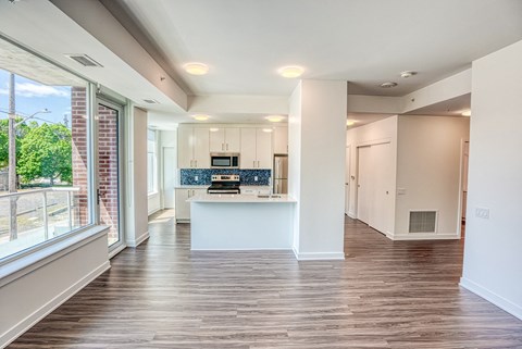 an empty living room and kitchen with a large window