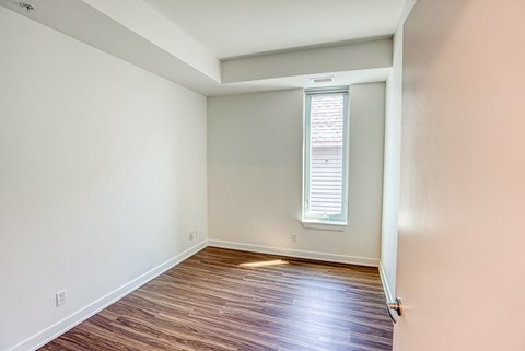 an empty room with wood flooring and a window