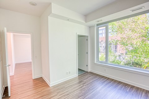 an empty living room with a large window and wood flooring