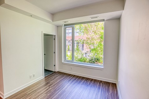 an empty room with a large window and wooden floors