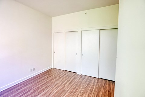 an empty room with wood floors and white closets